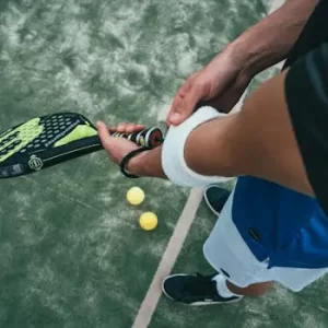 pexels-photo-1103829-1103829-1 Close-up of a male padel player adjusting wristband on a court. Sports action focused.