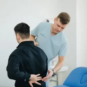 pexels-photo-20860586-20860586-1 Physiotherapist assisting a patient with back pain in a clinic setting.