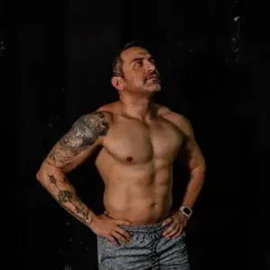pexels-photo-28455391-28455391-1 Fit man with tattoos confidently posing in a gym environment.